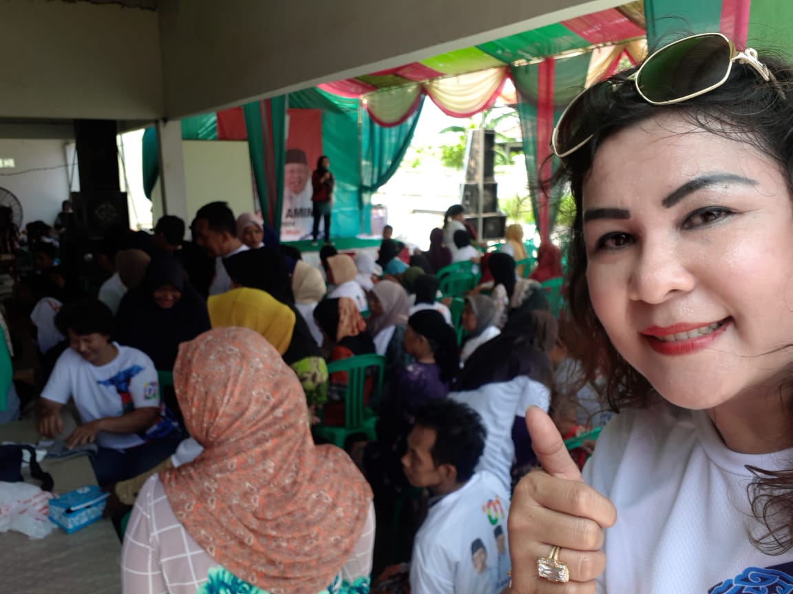 Ketua Umum Wanita Pejuang #01, Atiek Pasaribu berfoto dengan latar bakti sosial berupa tausyiah dan cek kesehatan serta pengobatan gratis bagi warga Desa Cipayung, Kelurahan Kampung Lilingir, Cikarang timur, Kabupaten Bekasi, pada Minggu (7/4/2019). (Foto: beritabata.co/ Hamdi Putra)